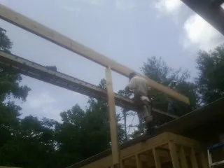 Carpenter setting a ridge beam over a new addition frame — Ice Dam Removal by Roofing Brothers in Cato
