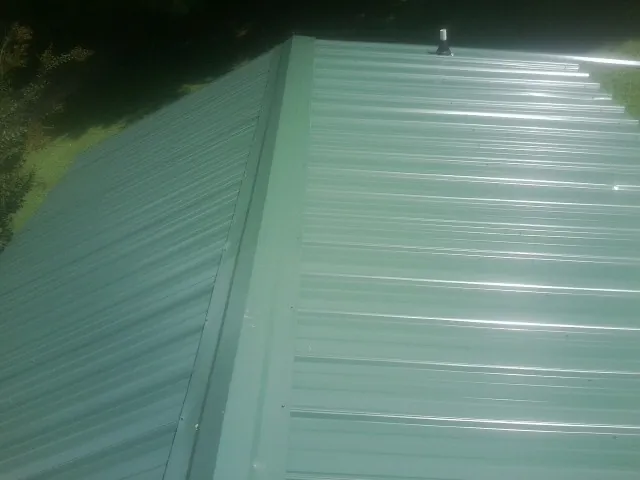 New green metal panels meeting at the ridge of a roof — Flat Roof Repair work by our crew in Cato
