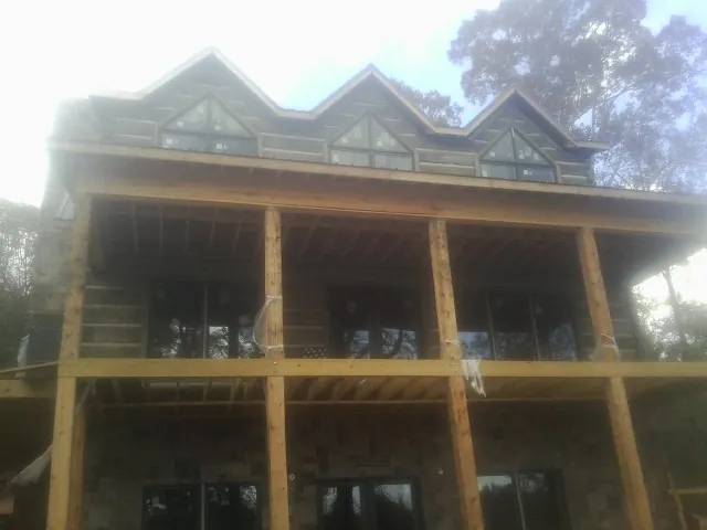 Dormers and porch framing on a large log home under construction — Roof Coating work by our crew in Cato
