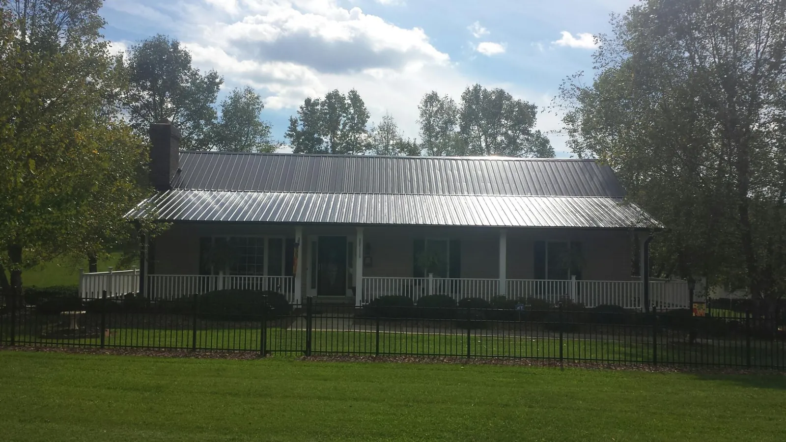 Gray metal roof on a brick ranch with a full width front porch — Gutter Guard Installation work by our crew in Cato