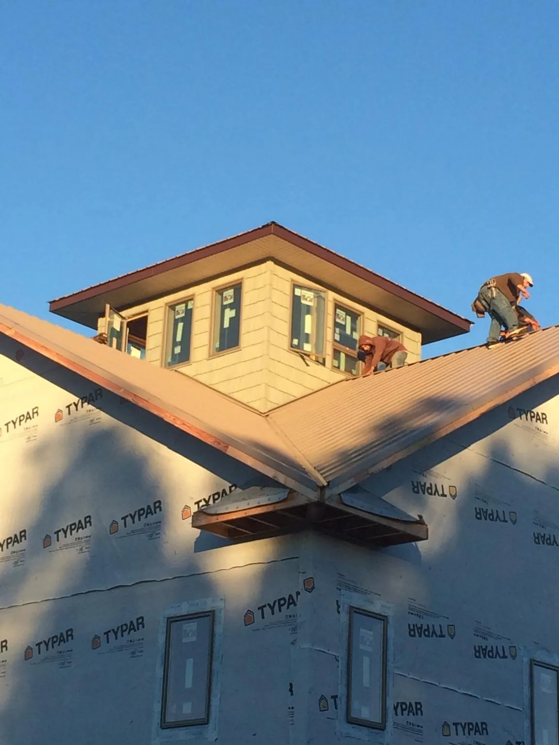 Roofers working around a rooftop cupola on a new metal roof at sunset — Roof Waterproofing in Cato by Roofing Brothers